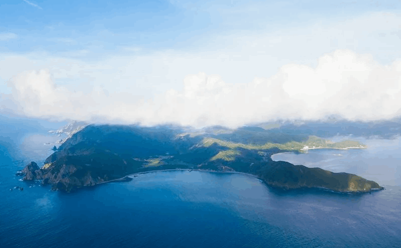 雲の下に浮かぶ緑の島を空から望む